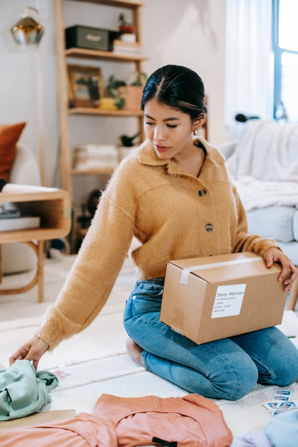 Carefully packing a clothing order into a parcel shipping box